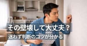 マンション間仕切り壁構造を確認する住戸内で壁を調べる人物