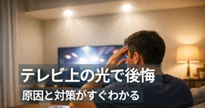ダウンライト テレビの上の眩しさに悩むリビングでテレビを見る人物